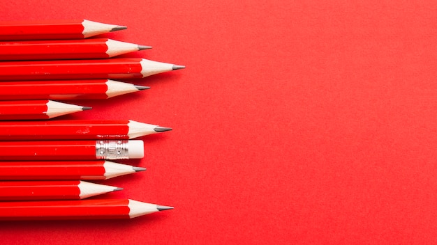 写真 赤い背景に他の鋭い鉛筆から立っている1本の鉛筆