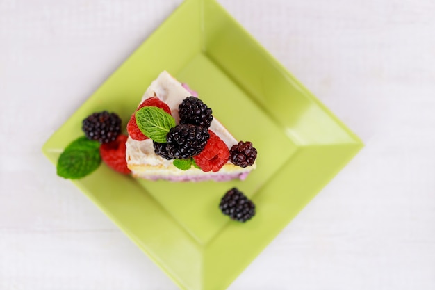 One piece of cake with fresh berries and mint on the top.