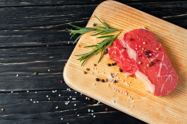 One pieces of juicy raw beef on a cutting board on a black wooden table