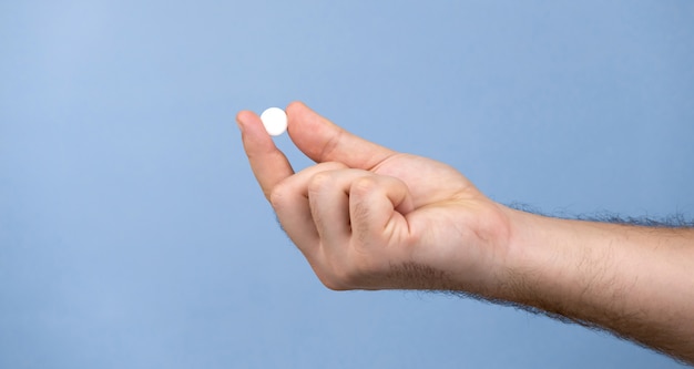 One pill in a male hand. A man holds pills in his hand.