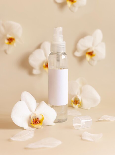 One pump dispenser bottle near white orchid flowers on light yellow close up Mockup