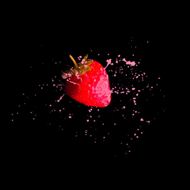 One rape strawberry in a flight splashing with pink yohurt on a black background Delicious and healthy nutrition