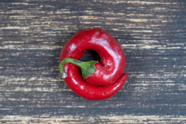 One red bell peppers on old wooden background close up top view