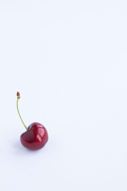 One red cherry on the white background. Closeup. Copy space. Location vertical.