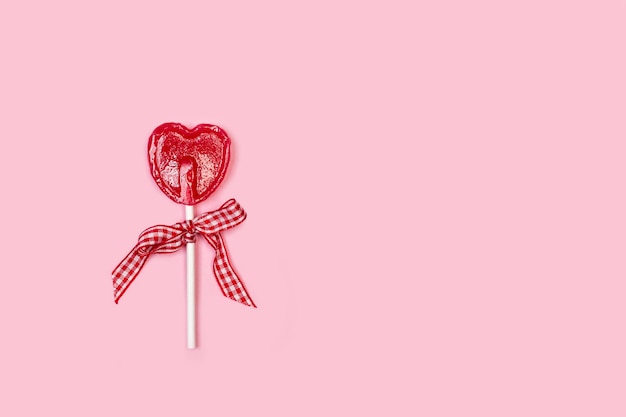 One red heart shaped lollipop on a pink background