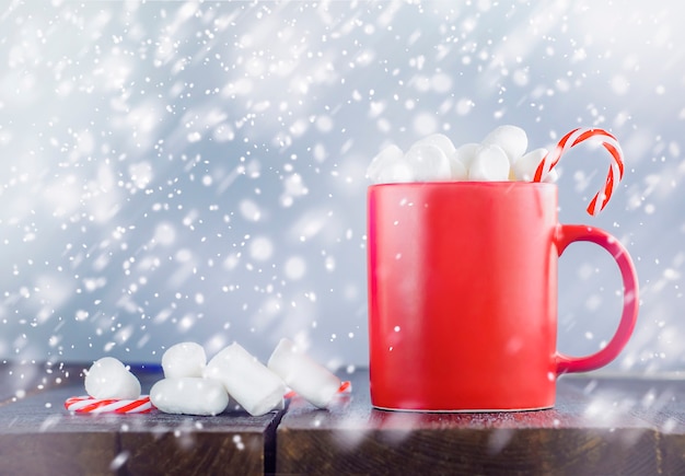 One red mug with hot chocolate on a wooden table outside