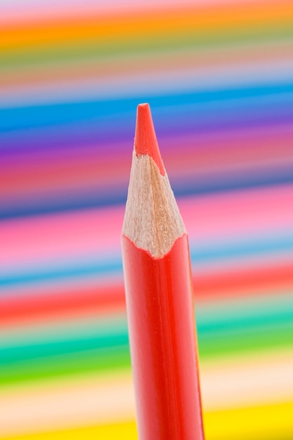 Photo one red pencil on a background of many colors