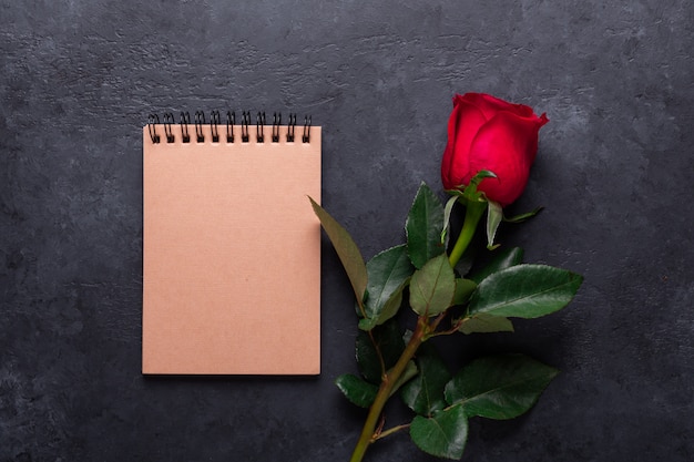 Photo one red rose, notebook on black stone. valentine's day note with copyspace