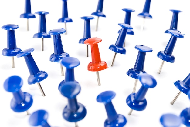 Photo one red thumbtack amid blue thumbtacks selective focus