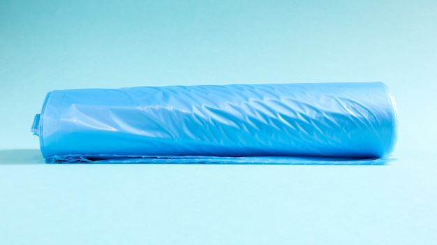 Photo one roll of plastic garbage bags in blue on a blue background. bags that are designed to accommodate garbage in them and used at home and placed in various garbage containers.