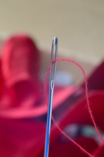 Close-up of a black thread and needle on a dark surface