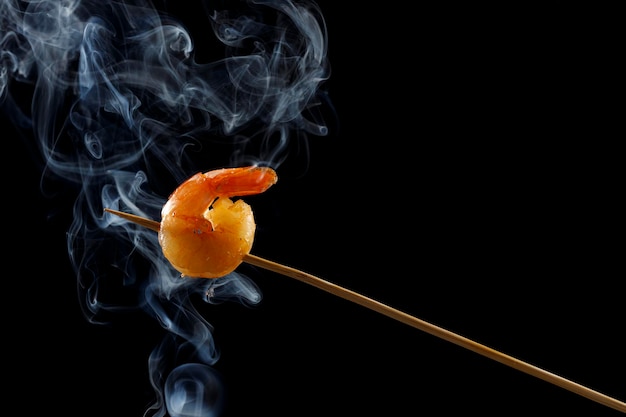 one shrimp on a skewer with smoke