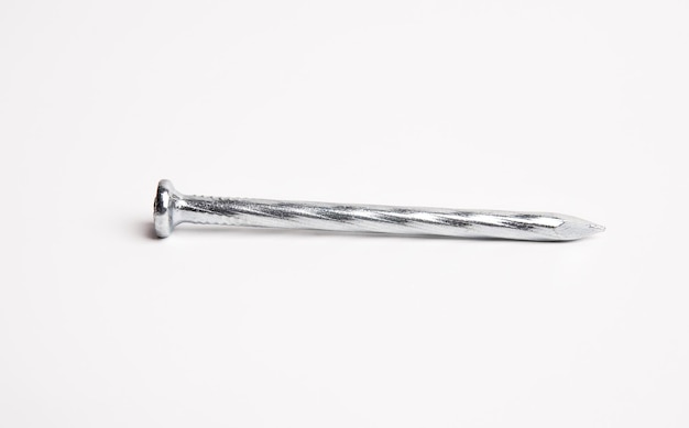Один серебряный блестящий острый металлический гвоздь крупным планом фото на белом фоне
