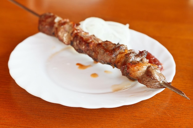 One skewer of lamb shishkebab on white plate