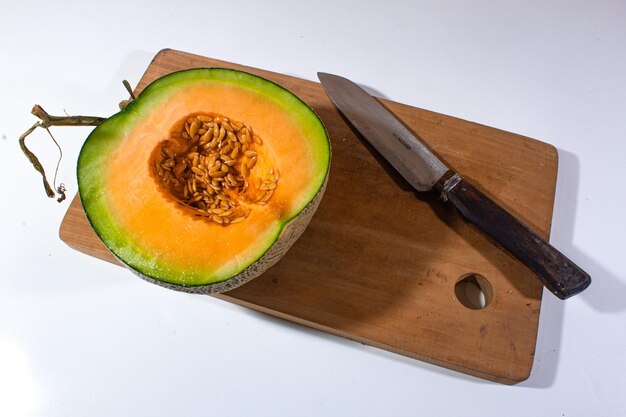 Photo one slice of fresh orange melon served on a wooden cutting board decorated with a knife