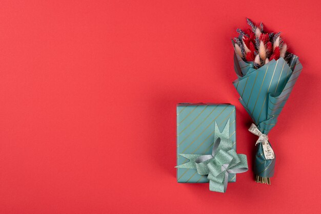 One small bouquet of lavender with lagurus and a gift in turquoise packaging on a red background.