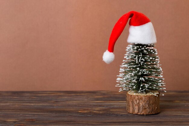 One small Christmas tree with santa hat on colored background new year decoration with copy space