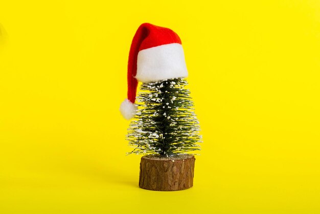 Photo one small christmas tree with santa hat on colored background new year decoration with copy space