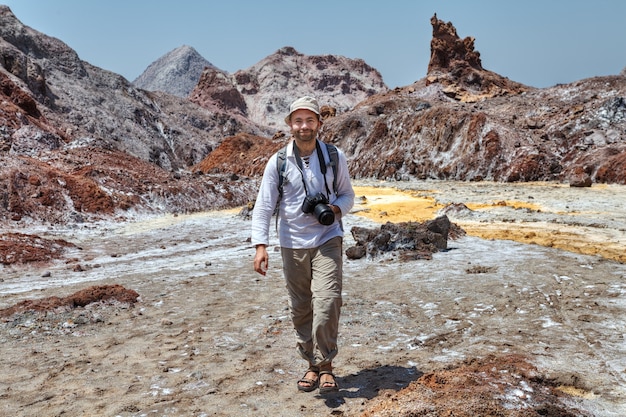 One smiling tourist Caucasian man walks by natural attractions with camera, Hormuz, Hormozgan, Iran.