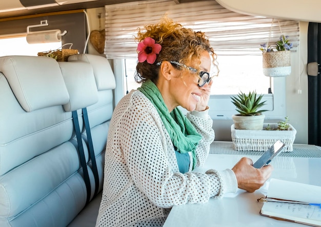 Photo one solo traveler woman enjoy time and indoor leisure activity inside a modern camper van motorhome using mobile phone and roaming wireless connection modern people and technology on travel concept