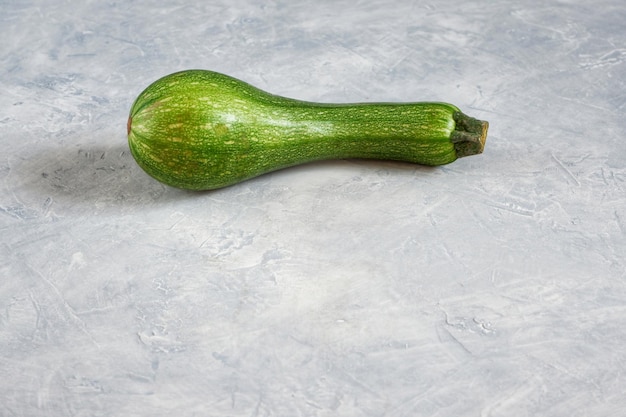 One spoiled zucchini on a gray background Ugly food concept organic vegetables With selective focus