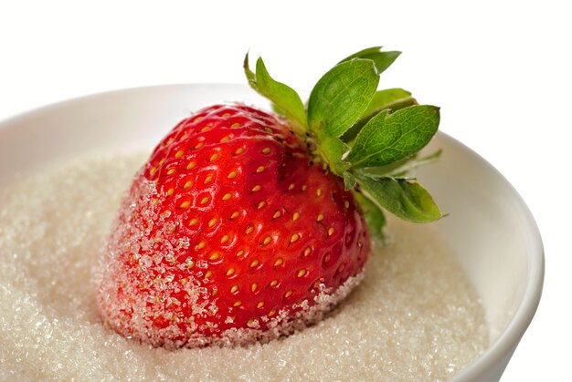 One strawberry in bowl with sugar isolaed on white