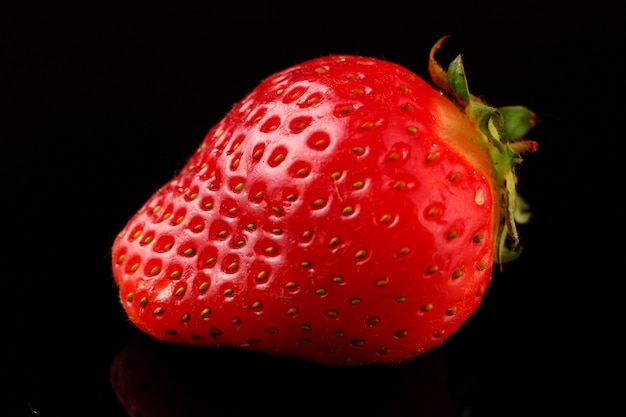 One strawberry on a dark surface