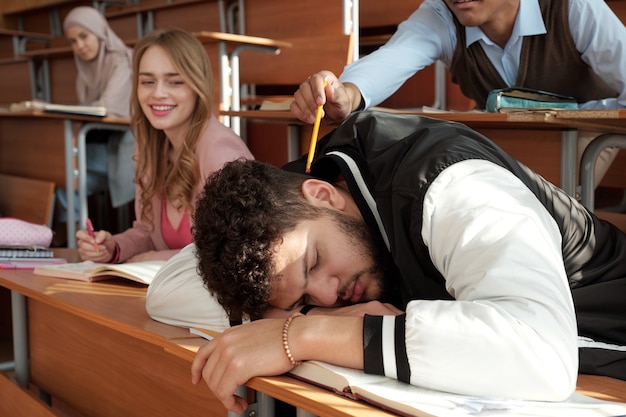 Foto uno degli studenti che cerca di svegliare il suo compagno di gruppo che dorme sulla scrivania