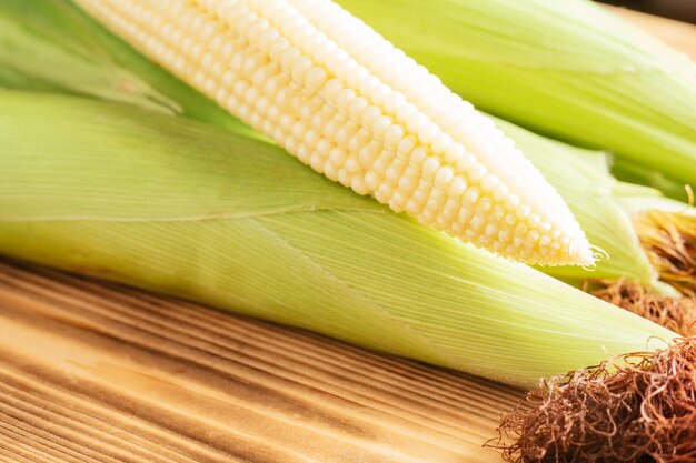 One sweet yellow raw milk corn cobs maize with white granule green fresh ingredient product Lie wooden background table