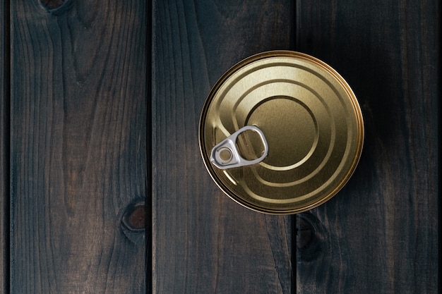 One tin with canned food on black wooden surface