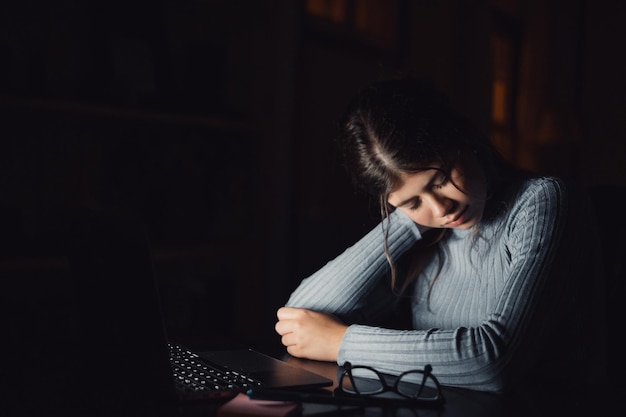 One tired and exhausted young woman feeling pain in her neck muscles after being working till late night Light of the screen on her face feeling badxA