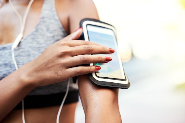 One touch is all it takes to set the rhythm Shot of an unrecognizable woman listening to music and using her cellphone while exercising outdoors in the city