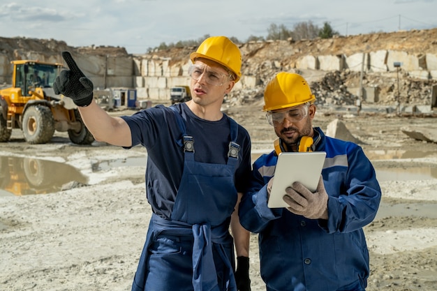 One of two builders showing unfinished construction to his colleague