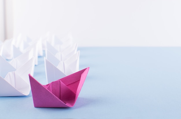 One Unique Pink Paper Boat among Many Ones. Different Paper Ships as Individuality and Leadership Concept