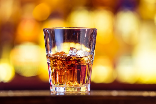 One whiskey with ice in a glass on the bar (closeup). Traditionally Irish drink