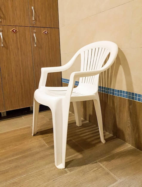 One white plastic chair stands near the wooden cabinets in the locker room of the sports club