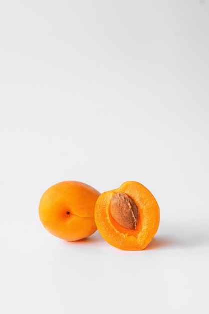 one whole apricot and half an apricot with a stone on a light background close-up