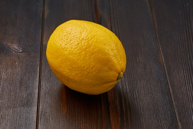 One whole bright yellow ripe delicious organic lemon on a natural wood