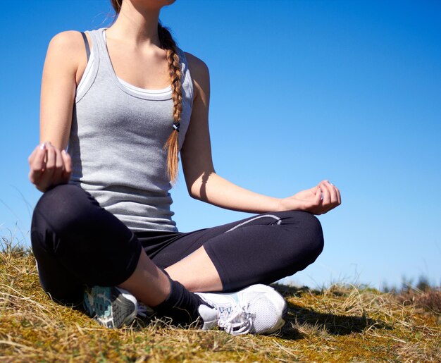 At one with nature Cropped shot of a young woman meditating outdoors in sports gear