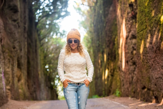 One woman adult age salking alone in nature park outdoor leisure tourism activity - hat and sunglasses in autumn season people enjoy time