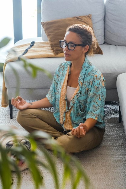 One woman at home having relax and meditation leisure oriental zen activity sitting on the floor in yoga lotus position. Wellbeing and healthy mental concept lifestyle. Interior balance concept female