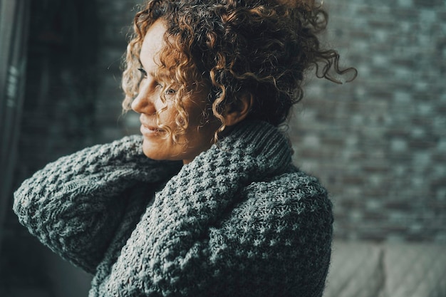 One woman at home indoor having relax stretching neck and shoulders wearing warm sweater in dark grey mood Serene female people loving herself concept lifestyle Inner life balance Independence