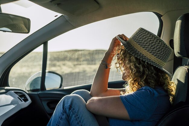 One woman sitting inside passenger car interior looking beautiful outside country side Concept of travel people and transport Free female in summer road trip adventure Wanderlust and destination