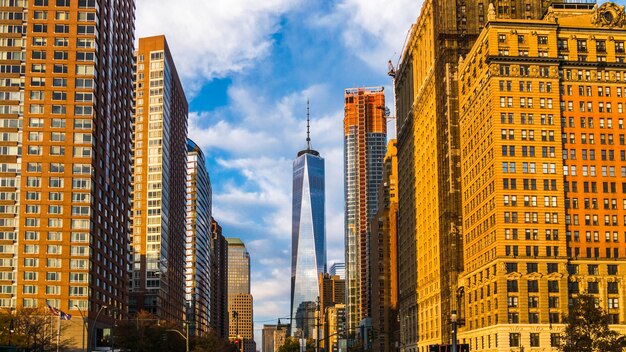 One world trade center amidst buildings against cloudy sky