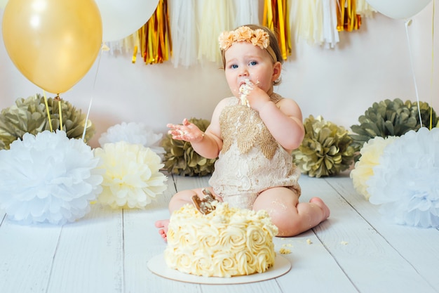 1歳の女の子が最初の誕生日ケーキのスマッシュパーティーでケーキを食べる。