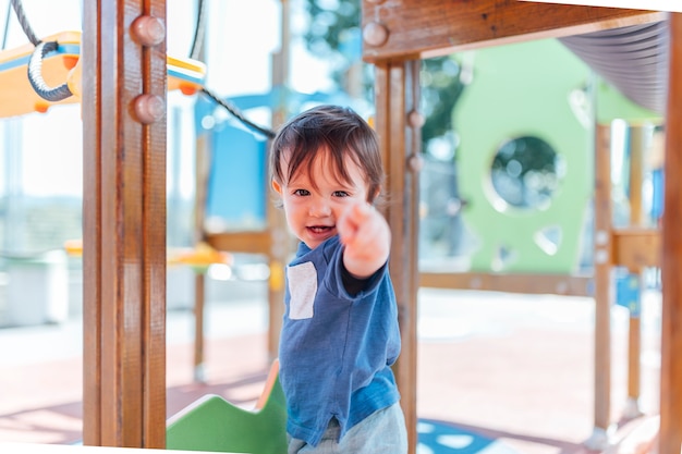 사진 놀이 공원에 있는 한 살짜리 아기가 앞에서 손가락을 가리키고 있습니다.