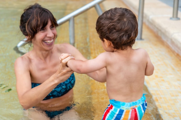 One year old baby in the pool enjoying the summer with his mother on summer vacation