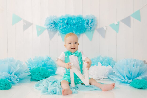 Un bambino di un anno festeggia il suo primo compleanno, tiene in mano la lettera n e sorride