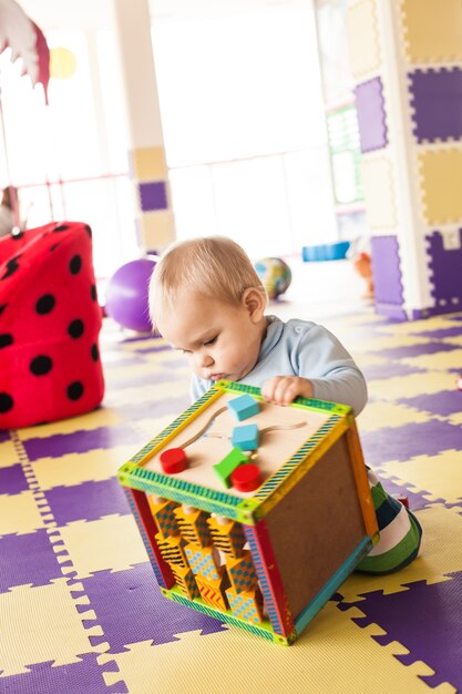 1歳の幼児の男の子は、プレイルームで細かい運動技能キューブで遊んでいます