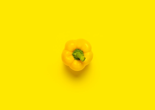 One yellow sweet pepper on a yellow surface. top view, flat lay